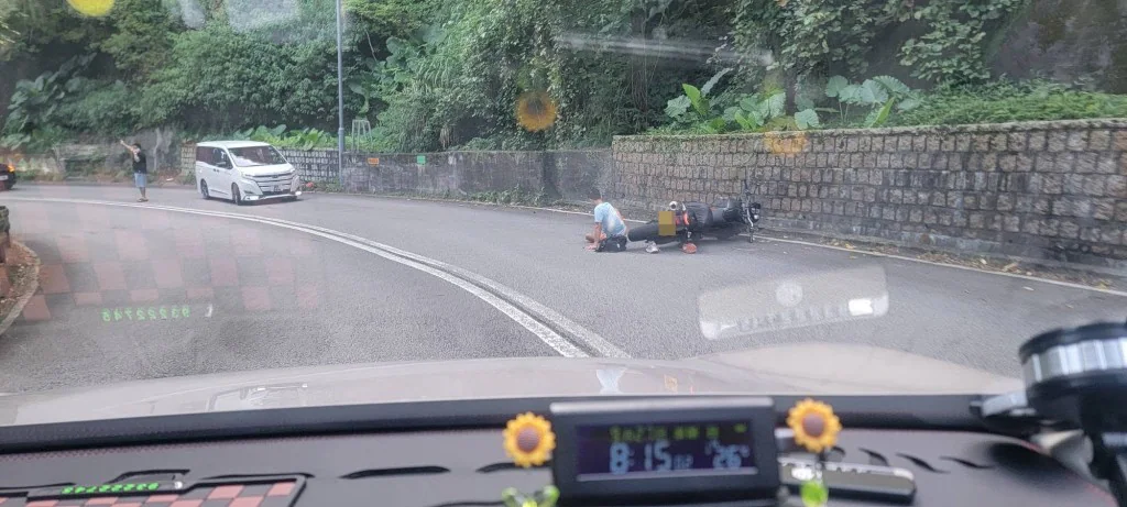 電單車在荃錦公路彎位倒地，遠處停泊有一輛白色私家車。
