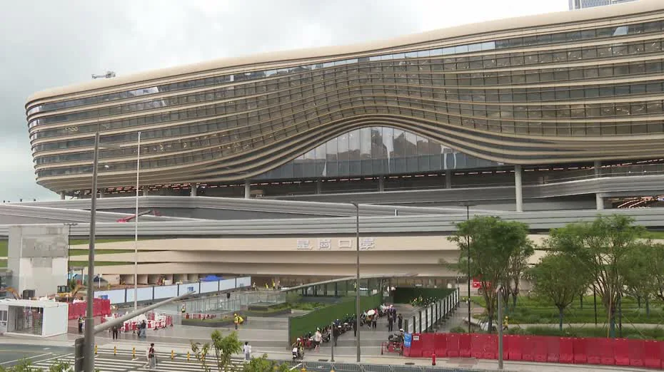 皇崗口岸聯檢大樓外觀呈流線型設計，下方設有行人通道及綠化空間，現場可見工程圍欄。