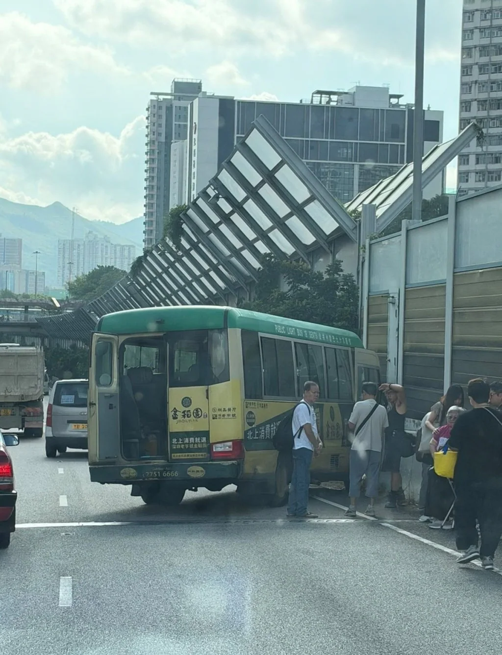 意外現場一輛綠色專線小巴停在路邊，車尾門打開，多名乘客站在車旁等待救援。