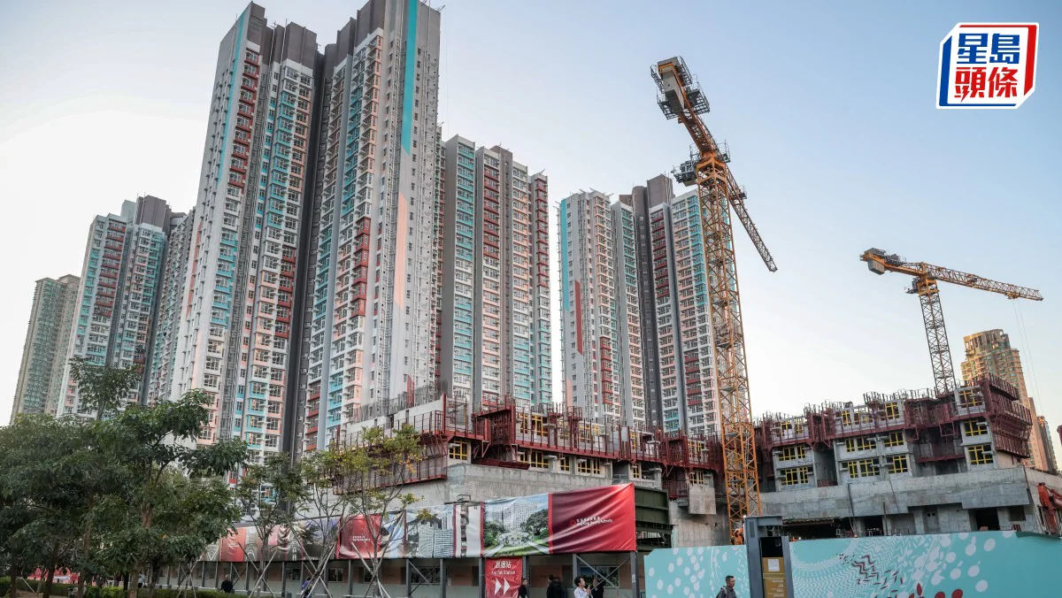 住宅建築地盤內設有吊臂起重機，背景可見多棟高層住宅大廈，圍板上貼有相關宣傳橫額。