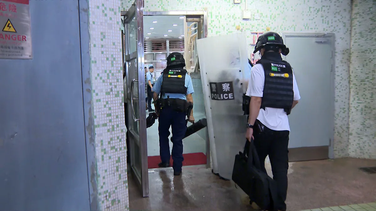 多名身穿避彈衣及頭盔的警員手持盾牌，進入慈正邨大廈室內範圍進行調查。