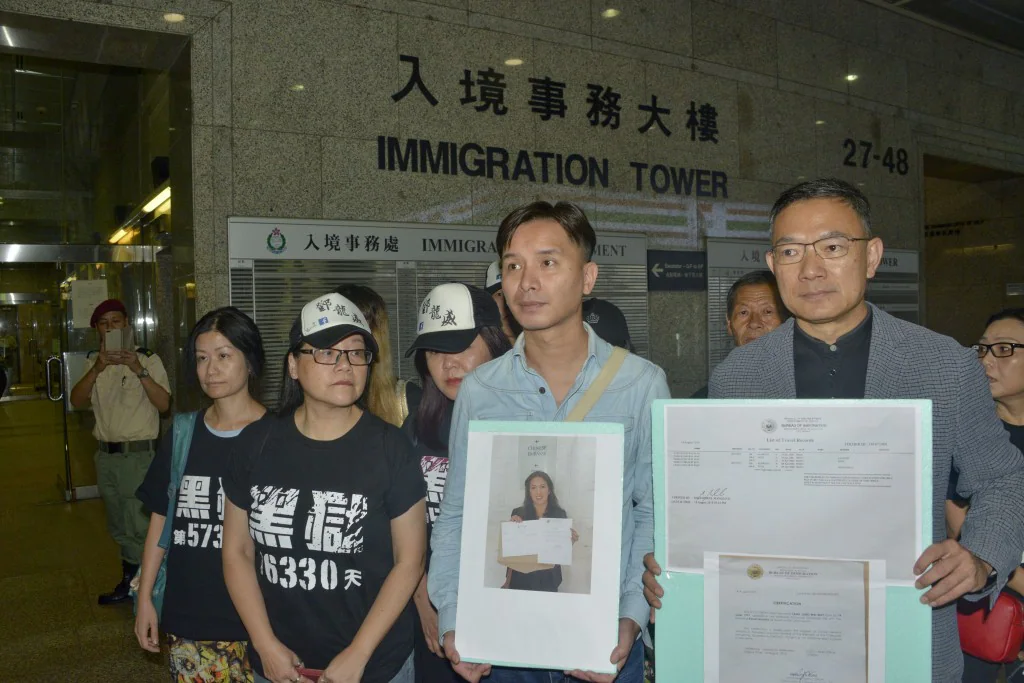 鄧龍威的家人與社會人士在灣仔入境事務大樓外，手持文件及照片為案件奔走。