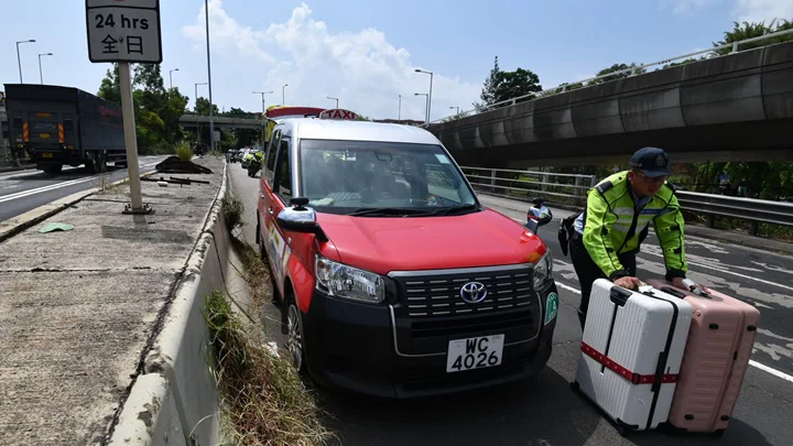 警務人員在呈祥道現場協助乘客搬運兩個行李箱，以便他們轉乘其他車輛。