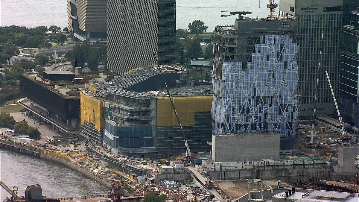 從高空俯瞰西九文化區的建築工地，多座建築物正進行工程，包括外牆圍上棚架及保護網的建築。