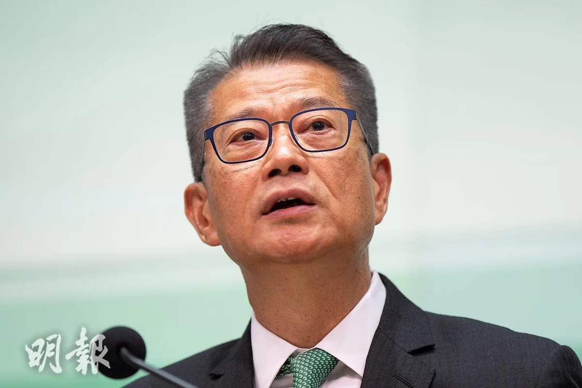 財政司司長陳茂波身穿深色西裝及綠色領帶，在麥克風前發言。