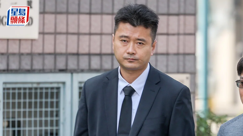 楊孟羲身穿深色西裝及黑色領帶，於高等法院外被傳媒拍攝。