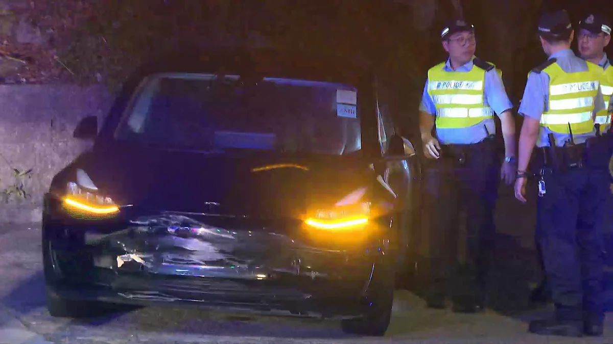 域多利道車禍現場，黑色私家車車頭損毀，警員在場調查。