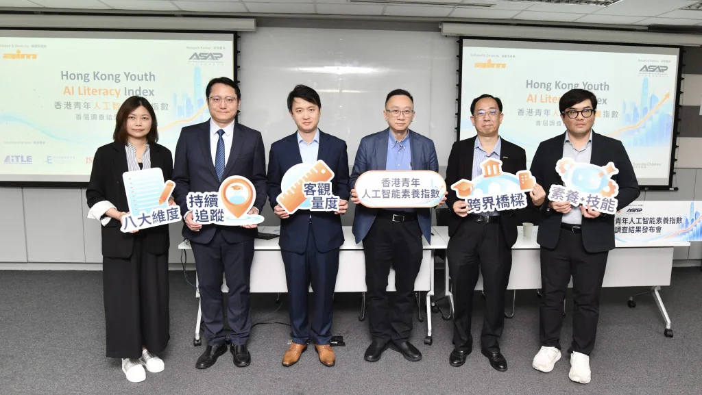 香港互動市務商會及亞太政策倡議研究所代表於發布會上合照，展示關於香港青年人工智能素養指數的標語牌。