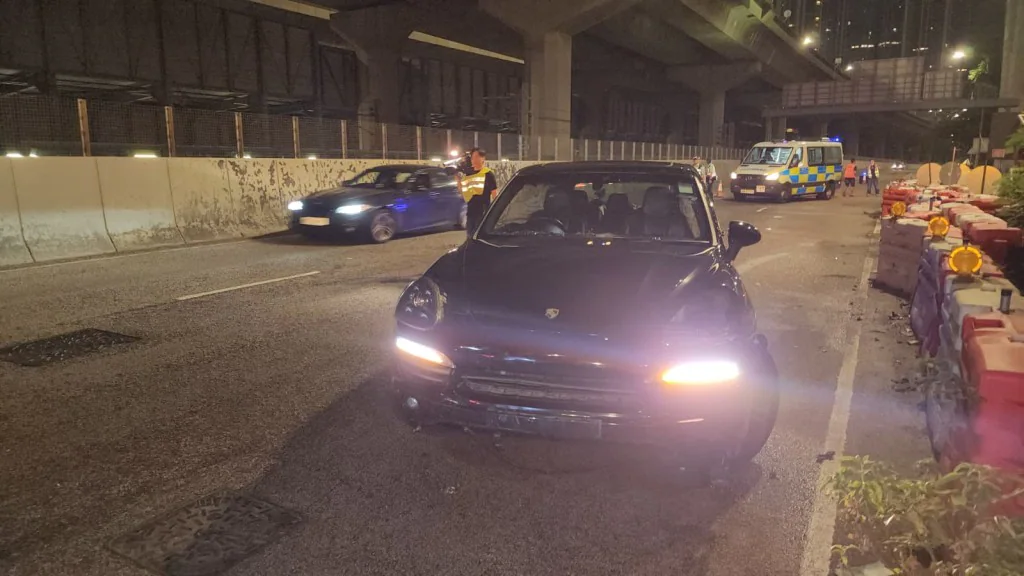 長沙灣連翔道車禍現場，一輛黑色私家車翻側於路中，多個水馬被撞倒，警員在場處理。