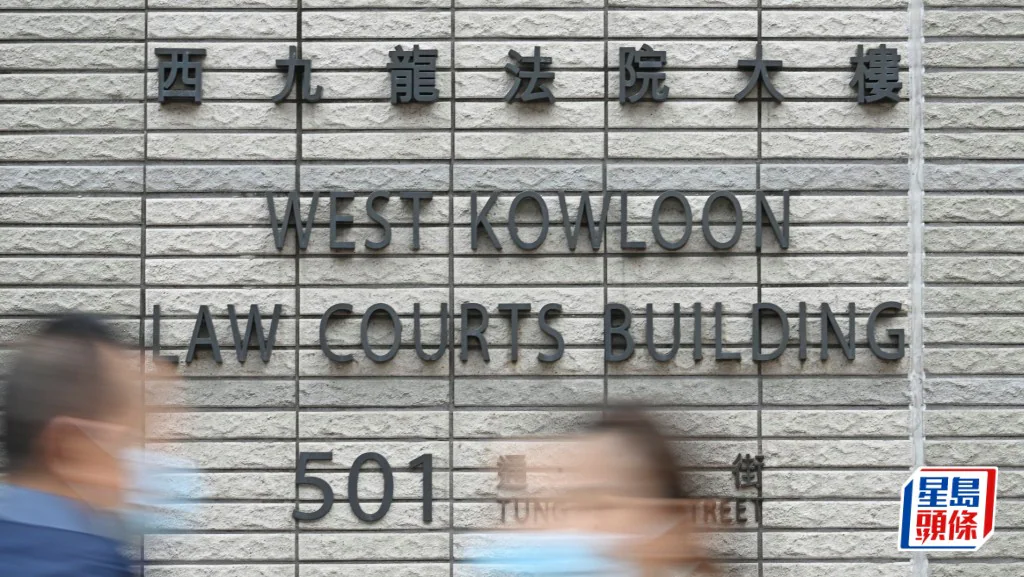 西九龍裁判法院大樓外牆，兩名途人經過法院門外。