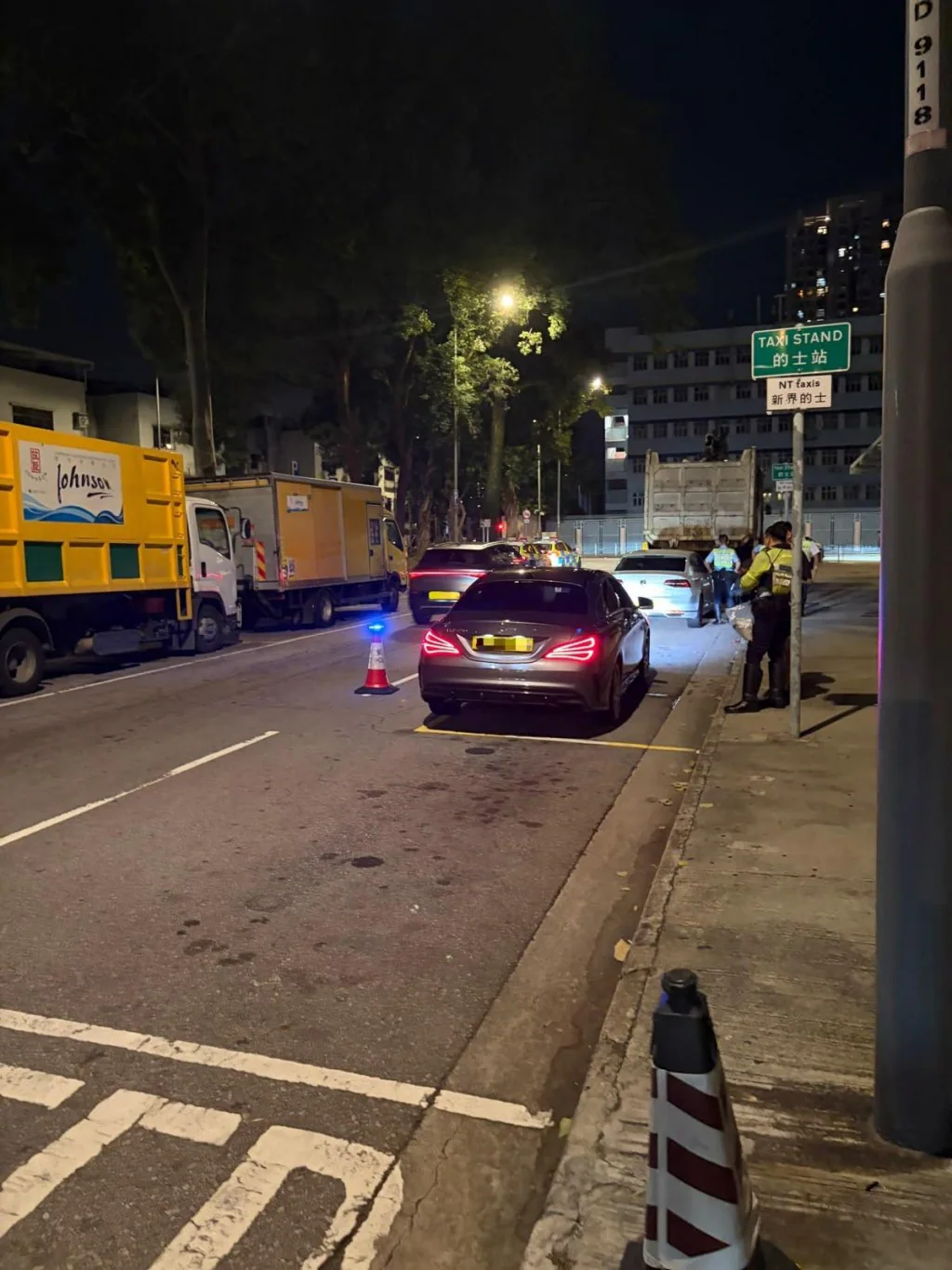 新界北總區交通部人員於夜間行動中，在設置雪糕筒的道路上截查車輛並進行酒精呼氣測試。